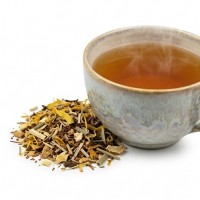 Tasse d'infusion Rooibos Bio ambrée fumante avec le mélange en vrac.