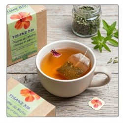 Une tasse fumante de Tisane du Matin Tonique et Détox bio AJC Nature sur un plan de travail en bois naturel